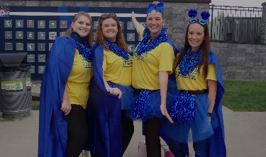 4 participants, dressed in yellow and blue, posing